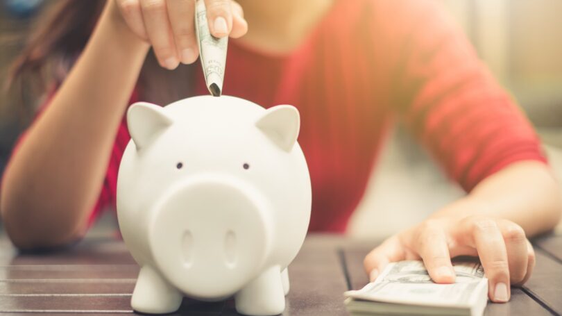 Woman Inserting Cash Into Piggy Bank Savings